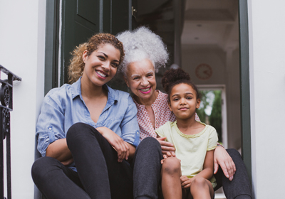Three generations of women sitting on a front step