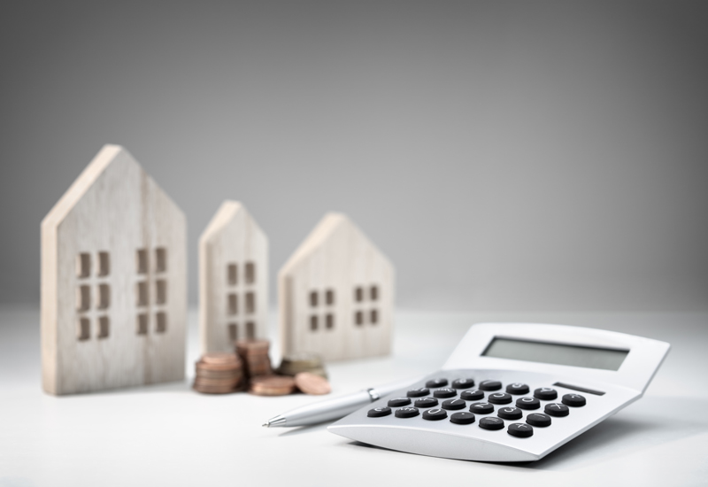 A pile of change, a calculator, and small wooden craft houses