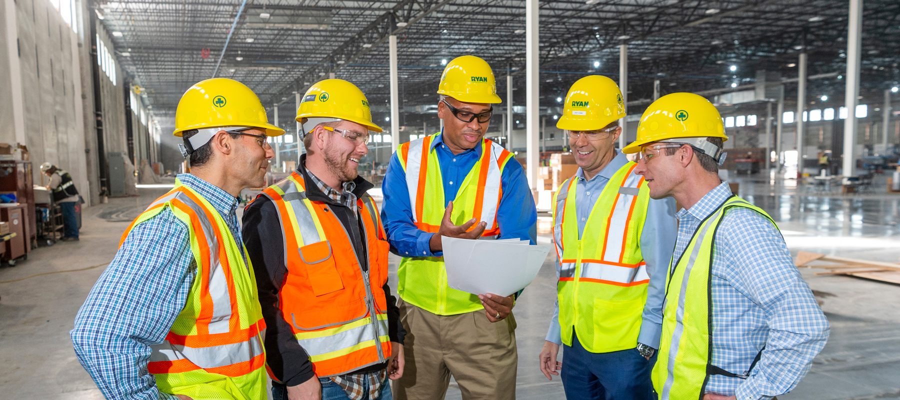 5 men in hard hats in a factory