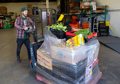 A man moving a large pallet of fresh food