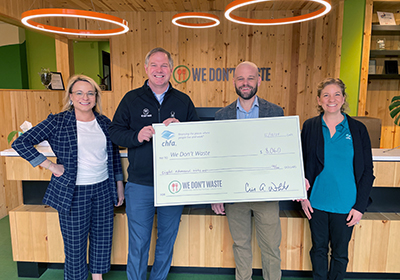 Four people smiling and holding a large check