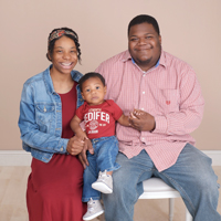 A mother and father posing for a photo with their toddler