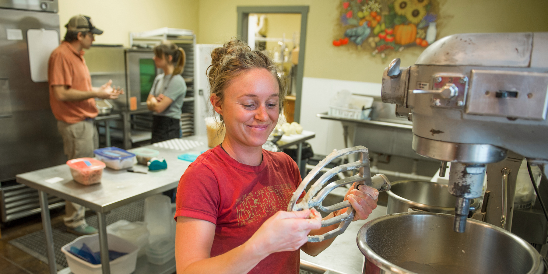 A woman smiling while mixing dough in a kitchen