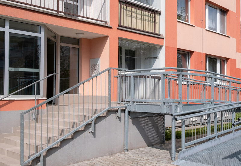 A red-bricked multifamily building with stairs and a ramp