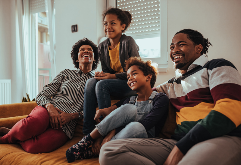 A family smiling in a living room with text that reads "building a legacy: a black homeownership series" and "colorado housing and finance authority"